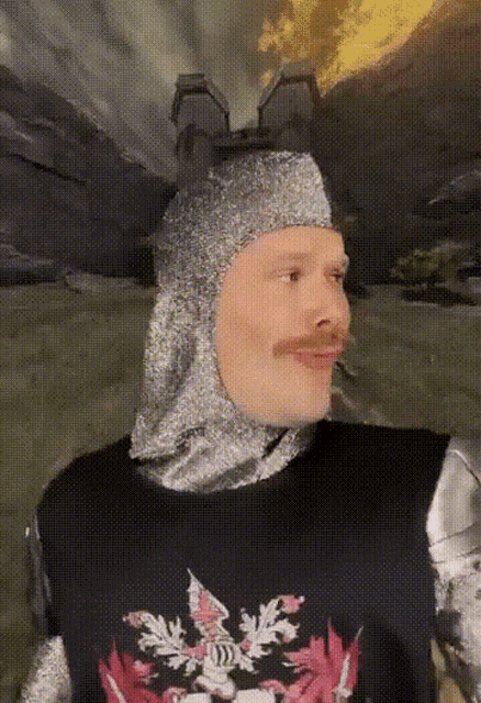 a man wearing a knight 's helmet and a black shirt with a dragon on it