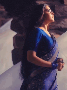 a woman wearing glasses and a blue saree has a heart on her head