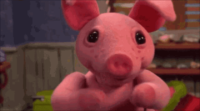 a pink stuffed pig is looking at the camera with a blurred background