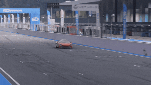 an orange sports car is driving down a race track