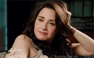 a woman is sitting on a couch and holding her hair .