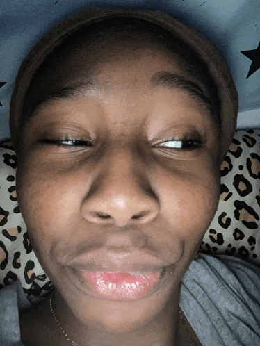 a close up of a person 's face with a leopard print pillow behind them