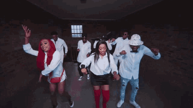 a group of people are dancing together in a hallway . one of the women is wearing bunny ears .