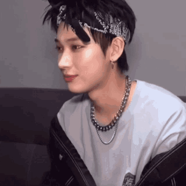a young man wearing a bandana and a necklace .