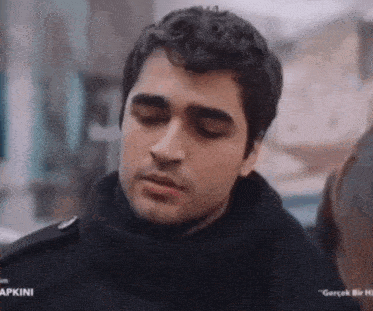a close up of a man 's face with his eyes closed and a scarf around his neck .