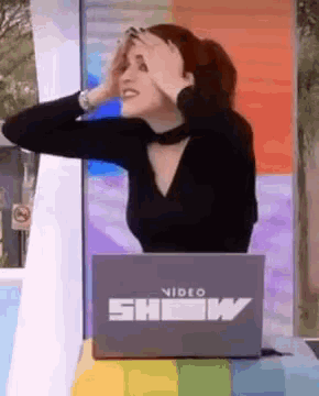 a woman sitting in front of a laptop that says show