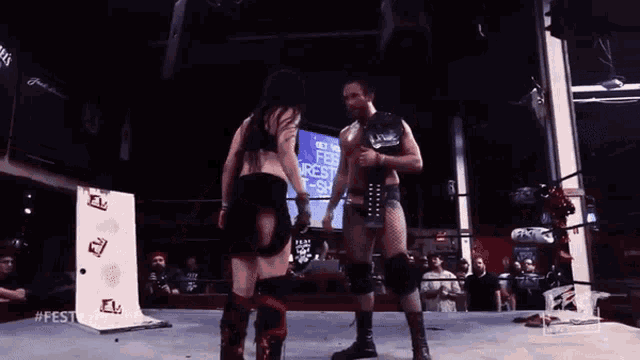 a man and a woman wrestling in a ring with a sign behind them that says fest