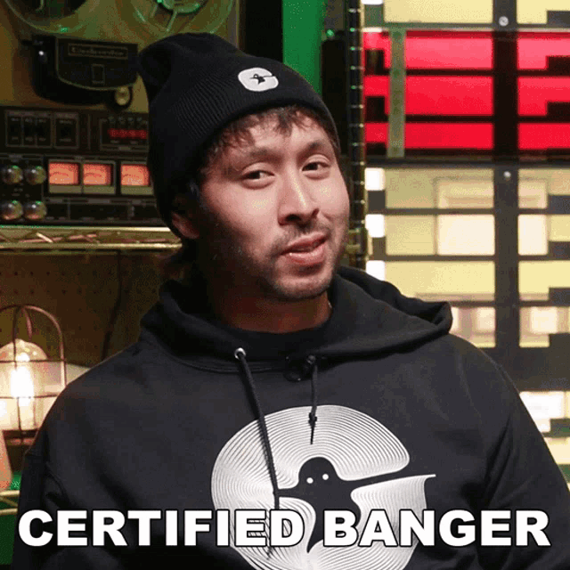 a man wearing a certified banger hoodie stands in front of a record player