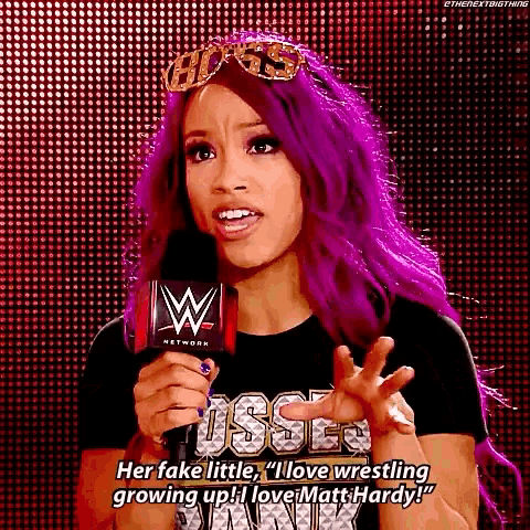 a woman with purple hair is standing in front of a microphone and talking into it .