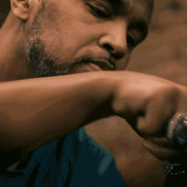 a man with a beard is wearing a blue shirt and a watch on his wrist