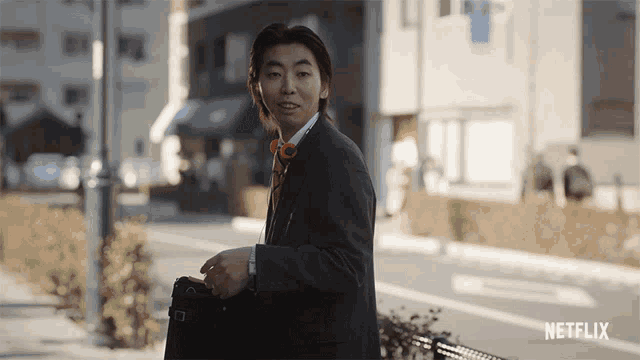 a man in a suit and bow tie is walking down a street with a netflix logo on the bottom