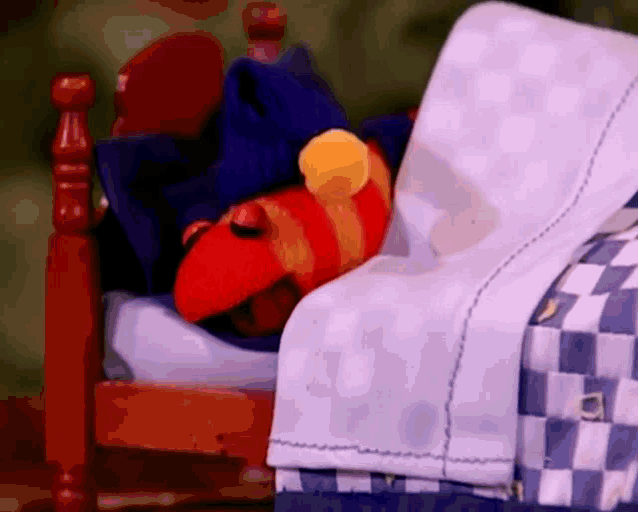 a stuffed animal is laying in a bed with a blue and white blanket .