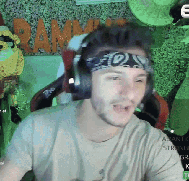 a man wearing headphones and a bandana is sitting in front of a sign that says ram