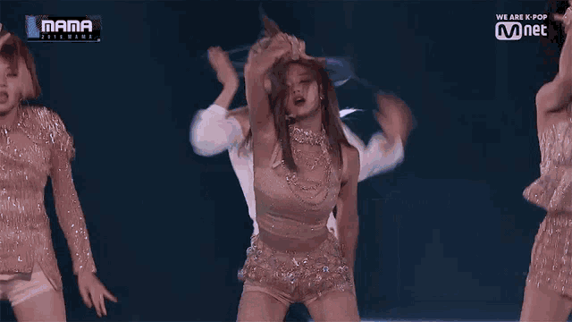 a woman in a crop top and shorts is dancing on a stage in front of a mnet banner