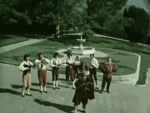 a group of men in costume are standing in front of a fountain .