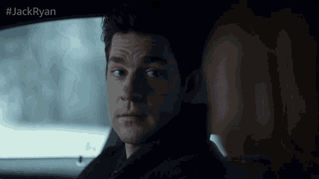 a man sitting in a car looking at a woman with #jackryan on the bottom right