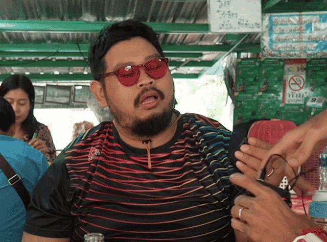 a man with a beard wearing sunglasses and a striped shirt