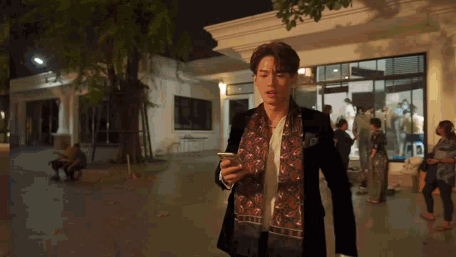 a man wearing a scarf and a jacket is looking at his phone