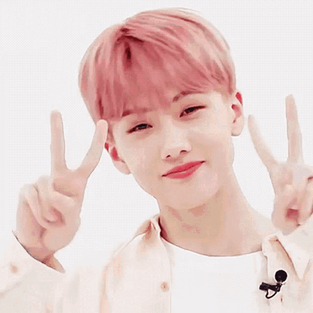 a young man with pink hair is making a peace sign with his hands