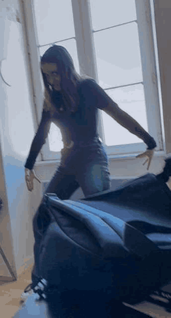 a woman is standing in front of a window with her arms outstretched .