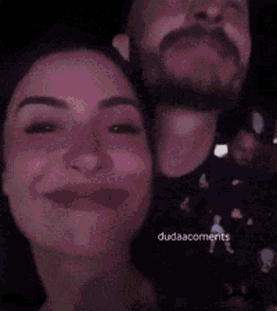 a man with a beard is laughing next to a woman with the word dudaacomments on the bottom right