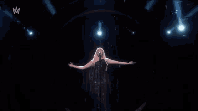 a woman is singing into a microphone while standing in the rain