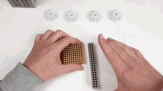 a person is holding a gold cube and a silver cube