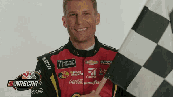 a man holding a checkered flag with a nascar logo in the background