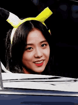 a girl wearing a yellow headband with horns is smiling