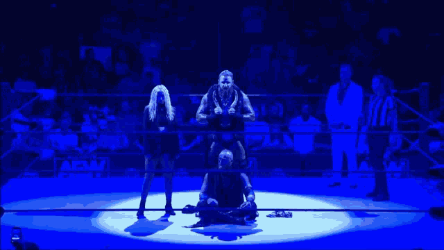 a wrestling ring with a few wrestlers and a sign that says aew
