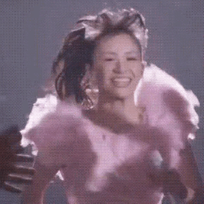 a woman in a pink dress is being hugged by a man in a black shirt .