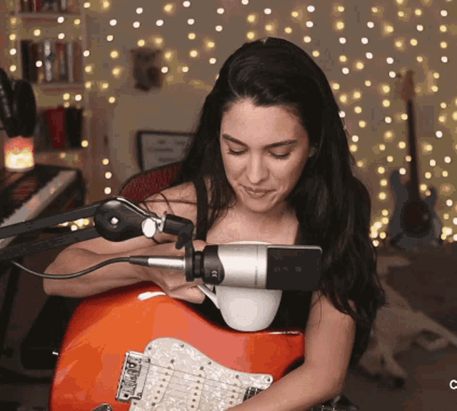 a woman playing an electric guitar with a microphone attached