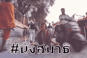 a man is sitting on the ground with a scooter in the background and a hashtag in a foreign language