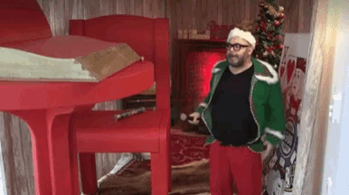 a man in a santa hat is standing in front of a christmas tree