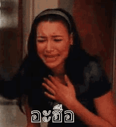a woman is crying and holding her chest with her hand .