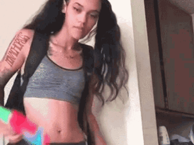 a woman with a tattoo on her arm is wearing a crop top and jeans .