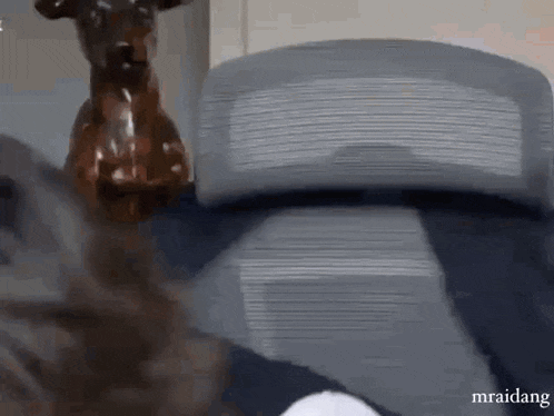 a statue of a deer is sitting on a chair next to a couch .