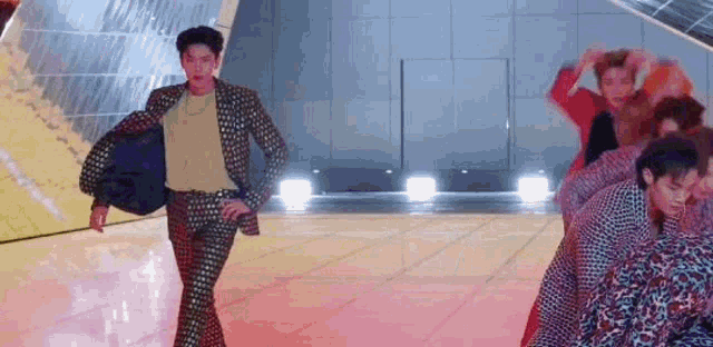 a man in a suit is dancing on a stage with a group of people .
