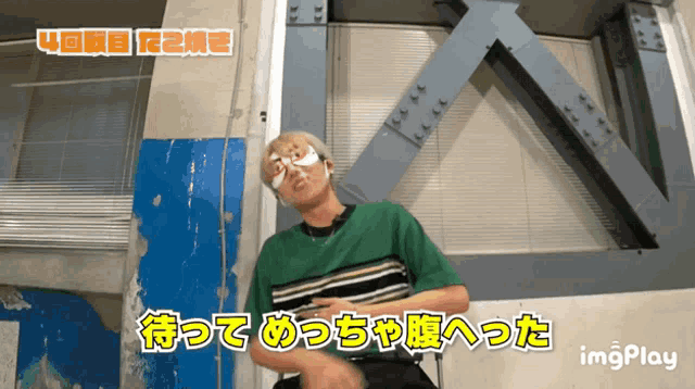 a man with a bandage on his eye is sitting in front of a wall with images play written on it