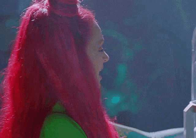 a woman with red hair is looking at a plant in a glass container