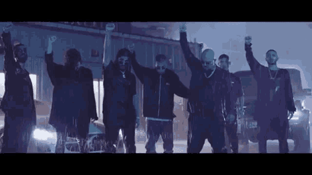 a group of men are standing in a line with their hands in the air .