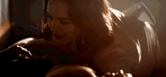 a woman is laying on a man 's chest and smiling