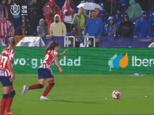 a woman kicking a soccer ball in front of a sign that says iberdrola