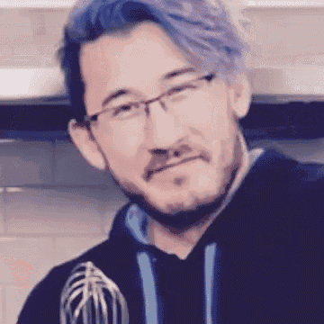 a man with glasses and purple hair is holding a whisk in his hand .