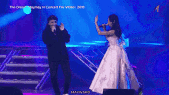 a woman in a pink dress singing into a microphone next to a man in a suit