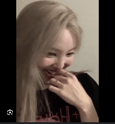 a close up of a woman covering her mouth with her hand while laughing .