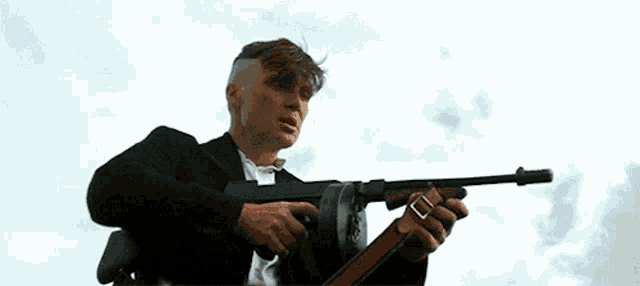 a man in a suit is holding a machine gun