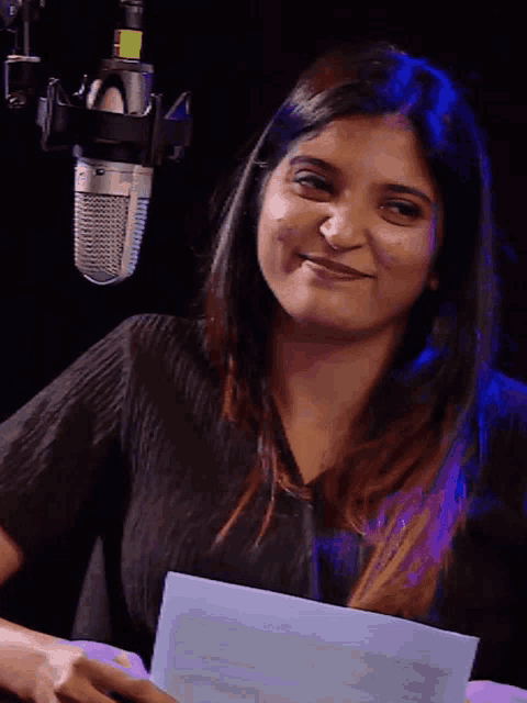 a woman is smiling in front of a microphone