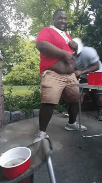a man in a red shirt is standing next to a red cup