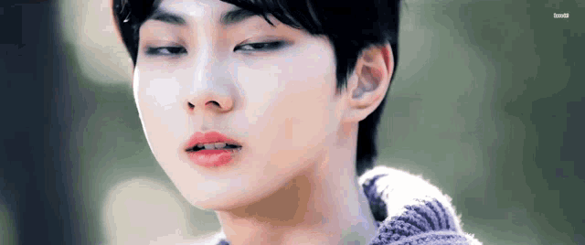 a close up of a young man 's face wearing a sweater .